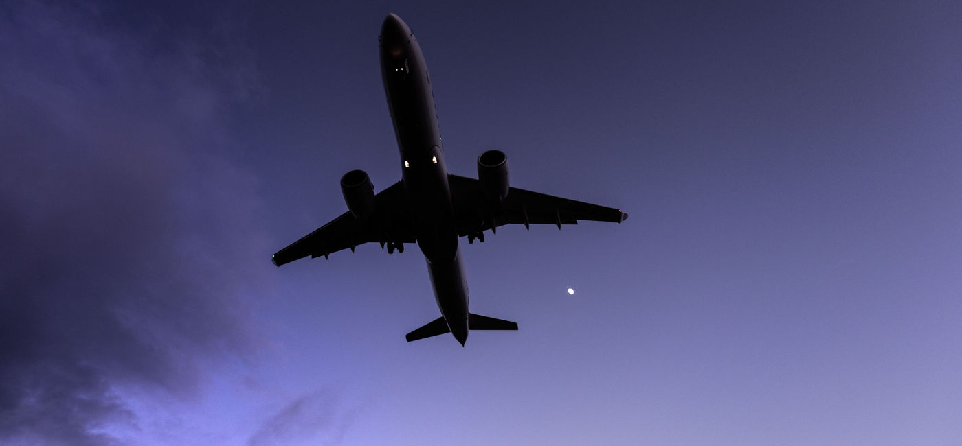 Image: A plane flying at night (Photo Credit: Adobe Stock / Raphael)