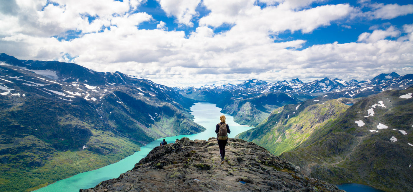 Image: A woman stands atop a peak in Besseggen, Jotunheimen, Norway. (Photo Credit: ajwk / Adobe Stock)