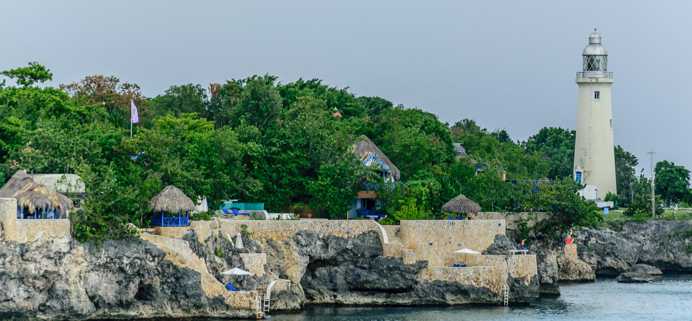 Image: The Negril Lighthouse beside a cliffside hotel resort on the coast of Negril, Jamaica. (Photo Credit: Debbie Ann Powell)
