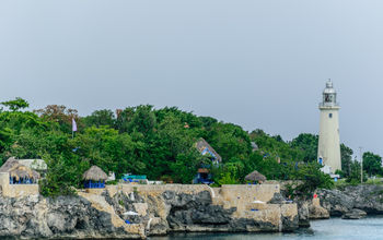 The Negril Lighthouse beside a cliffside hotel resort on the coast of Negril, Jamaica.
