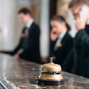 Hotel staff working at reception counter with service bell.  
