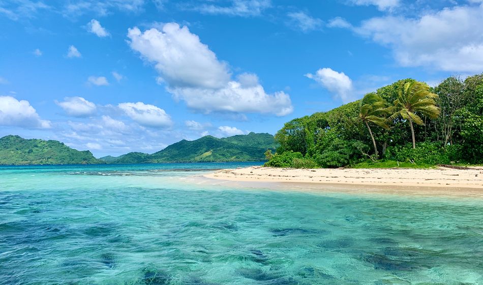 Island with turquoise water, white sand beach, blue sky