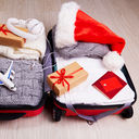 Suitcase with Christmas gifts and a Santa hat.